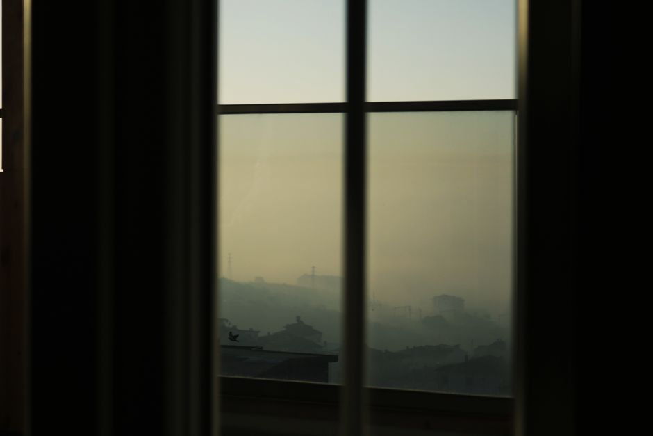A calming view of fog-covered mountains seen through a window at dawn, creating a serene atmosphere.