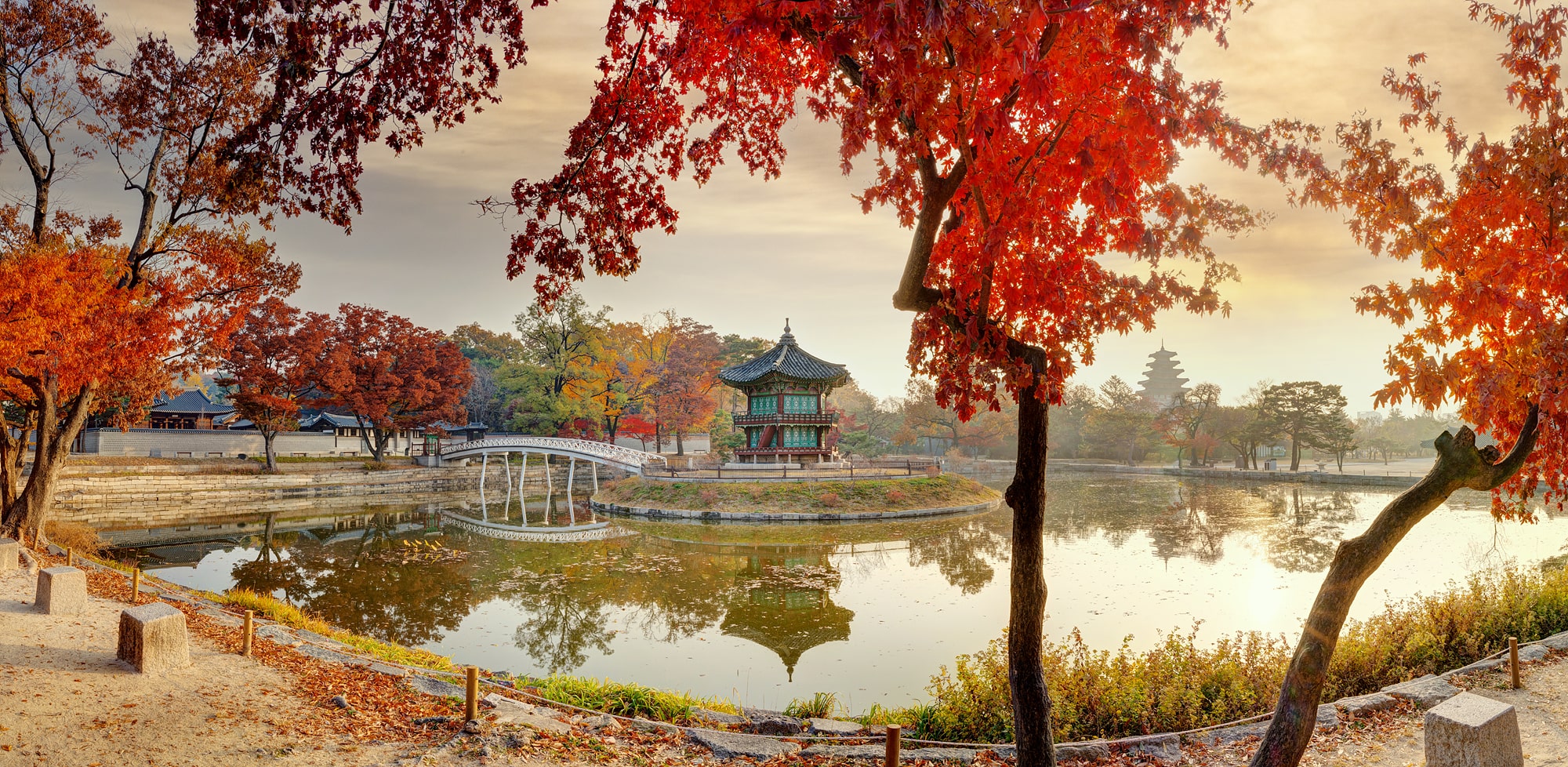 연못에 정자가 있고 그 주변에 단풍이 든 나무들이 보인다.
