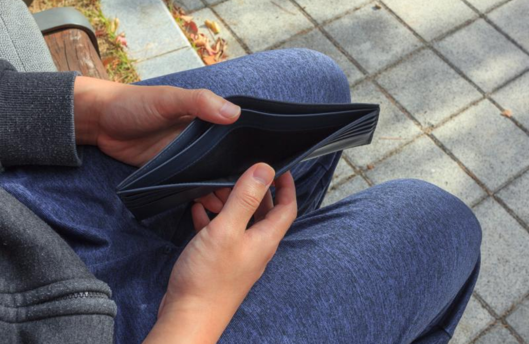 텅빈 지갑을 들여다보는 남자.