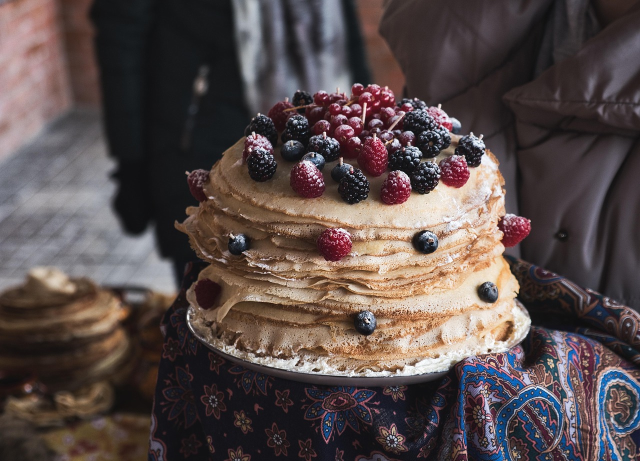 넓은 접시에 밀가루로 만든 펜케익 위에 블루베리와 산딸기가 위에 많이 놓여있는 사진입니다.