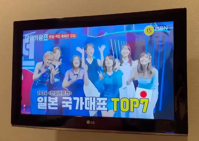 한일-갈색 벽에 걸린 TV안 한일가왕전이 방송되고 있는 이미지