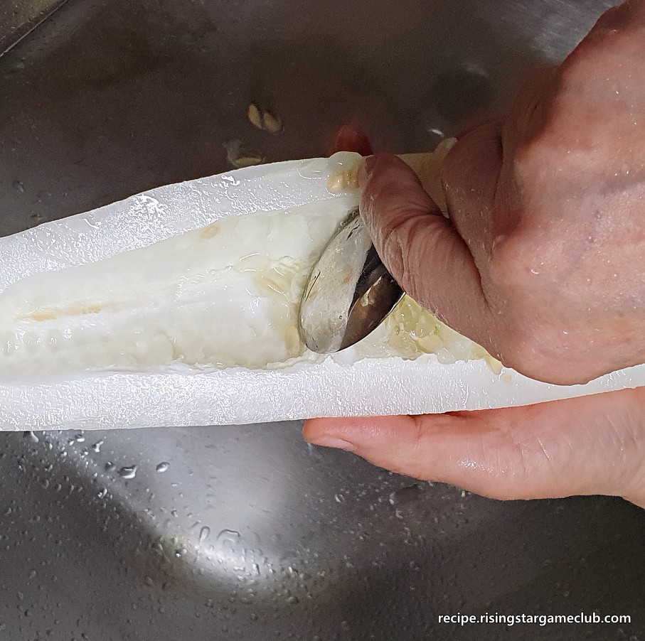 노각 무침을 하기 위해 반으로 자른 노각의 씨앗 부분을 제거하는 사진