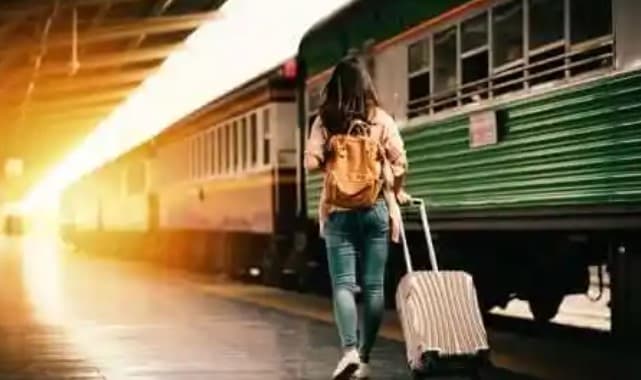 기차역에서 기차 옆으로 가방과 캐리어를 끌고 가고 있는 여성의 뒷 모습