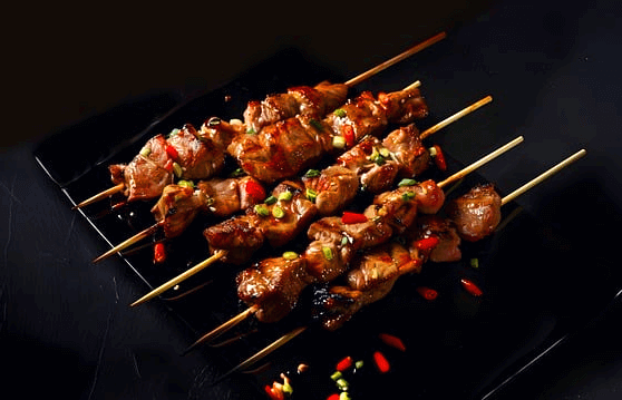 네모난 검정 접시에 닭꼬치가 가득하다. 잘 익었고, 빨간 홍고추가 뿌려졌다.