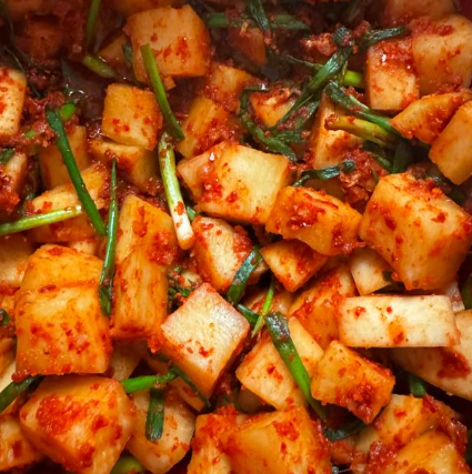 무를 고춧가루 양념에 빨갛게 버무린 깍두기. 무를 한 입 크기 정육면체로 자르고 파를 비슷한 길이로 잘라 같이 섞어 놓은 모습.