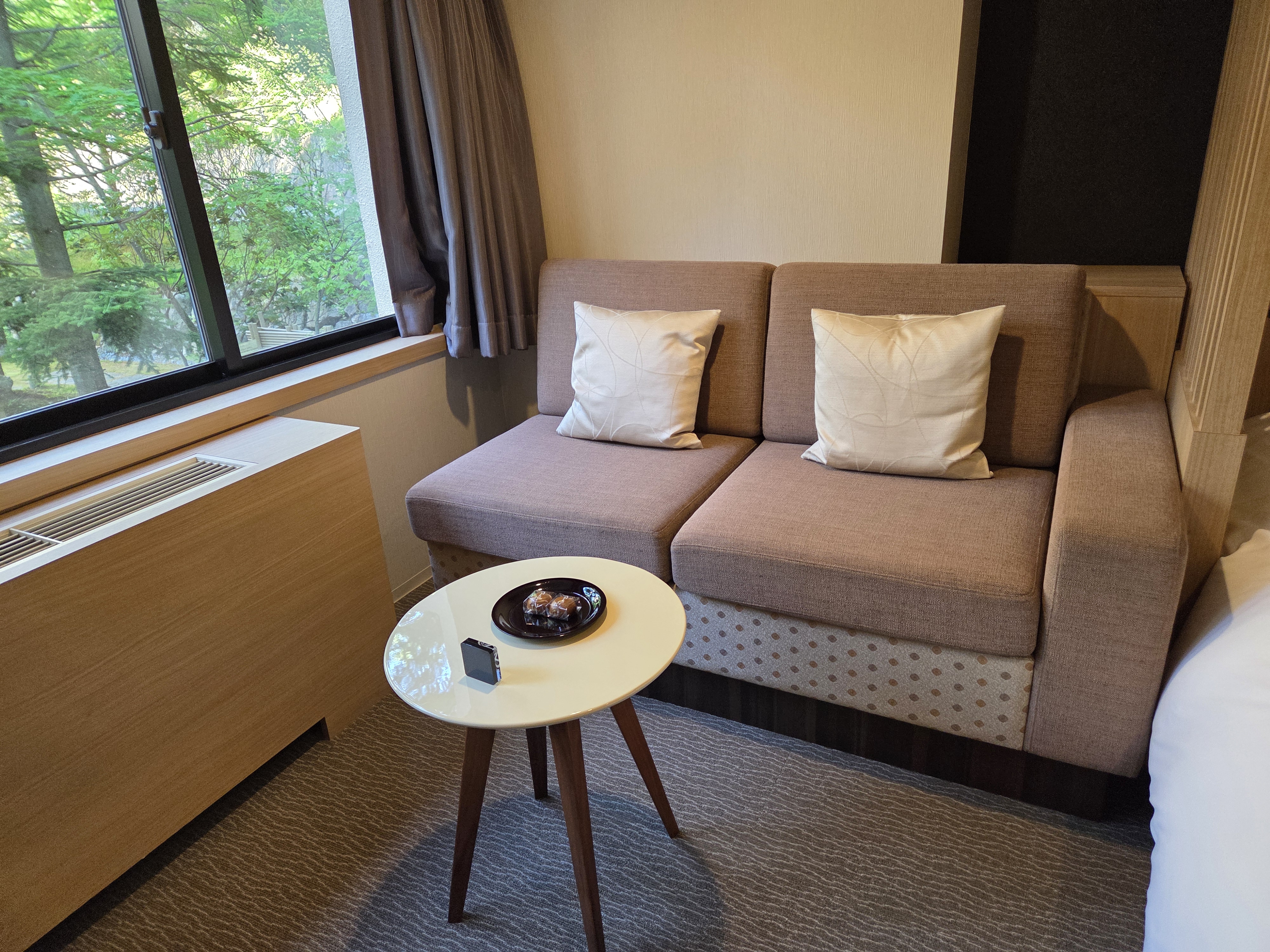 창가 소파와 원형 테이블이 있는 노보리베츠 료칸 다이이치 타키모토칸 동관
