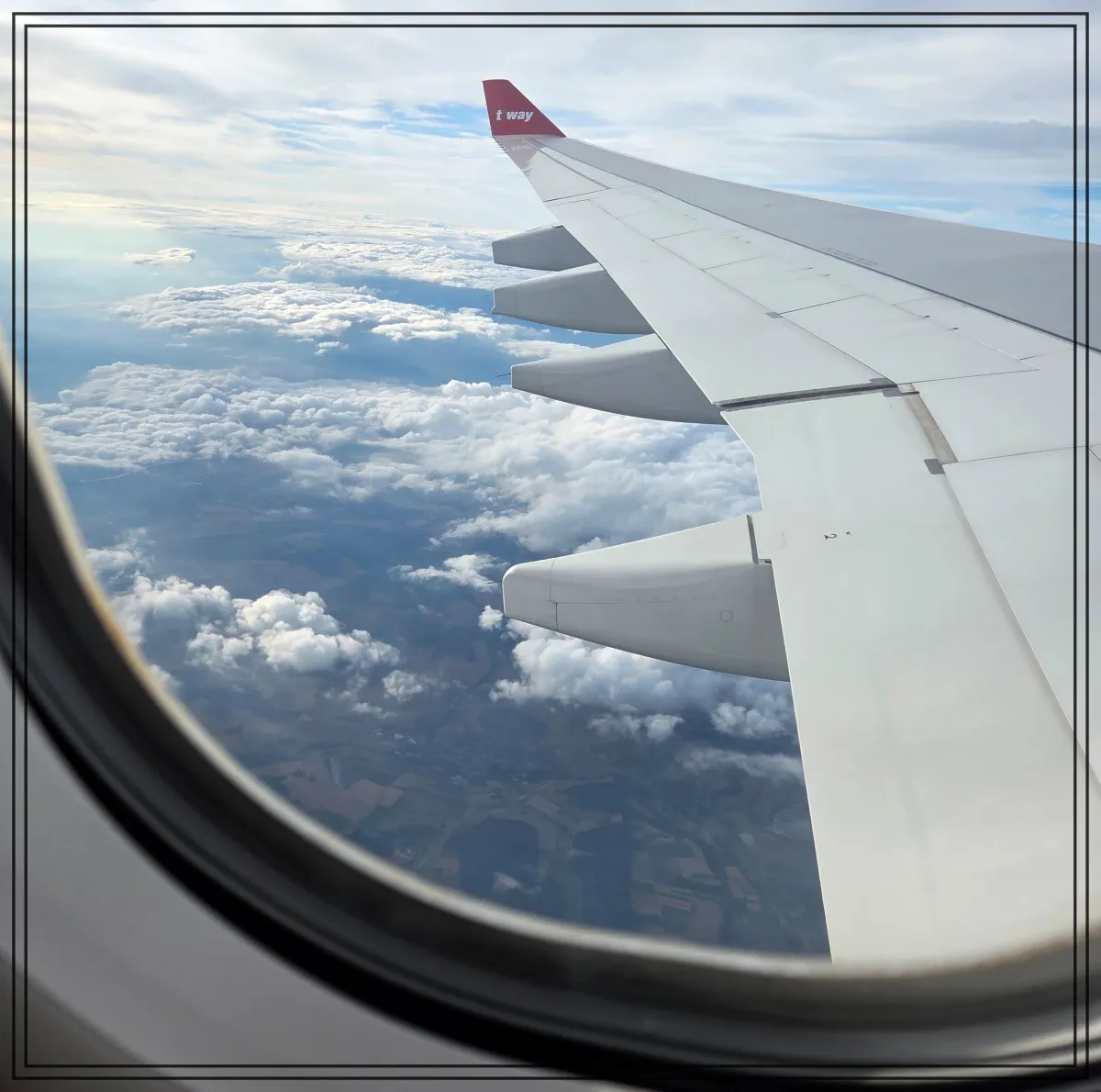 티웨이항공-비행기창밖풍경-하늘날며-구름과-지상풍경보이는장면-날개끝로고보임