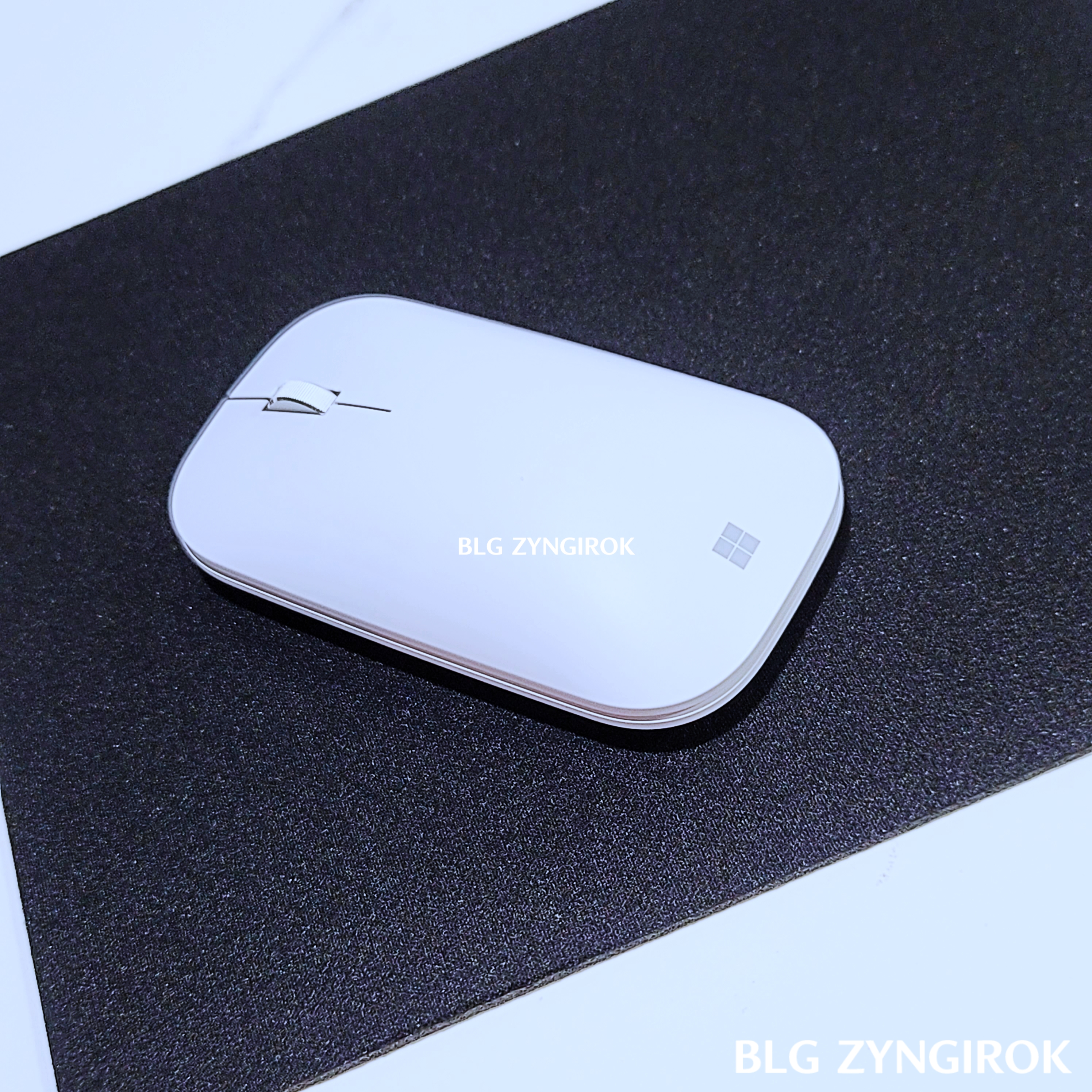 마우스 패드 위에 MS 모던 디자인 마우스가 놓여있다.