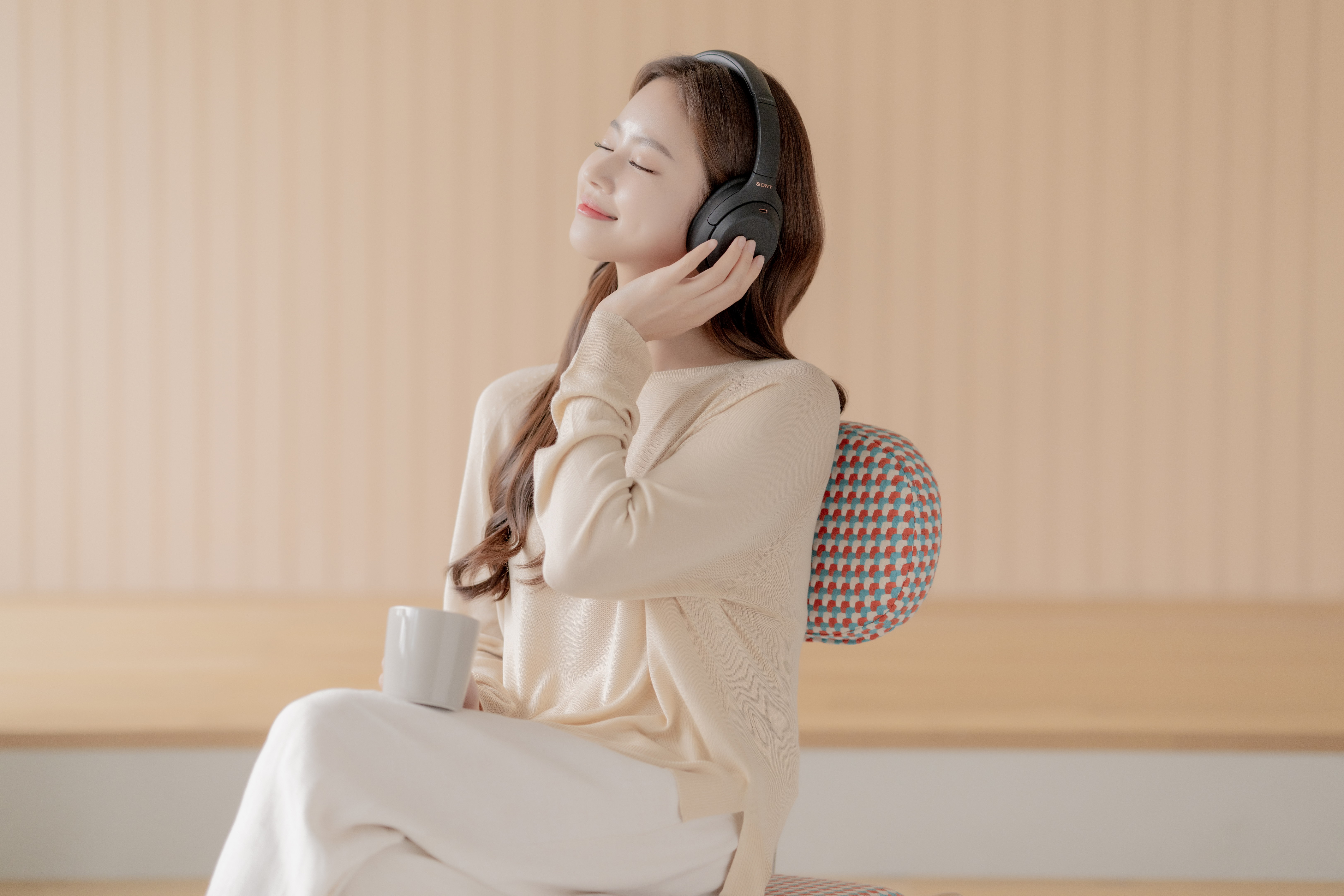 소니 헤드폰으로 음악을 듣고 커피를 마시며 쉬는 여자