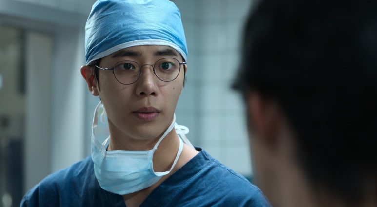 수술실에서 수술복을 입고 진지한 표정을 짓는 의사