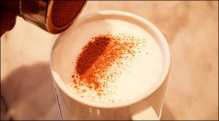 음료 위에 계피가루를 뿌리는 모습