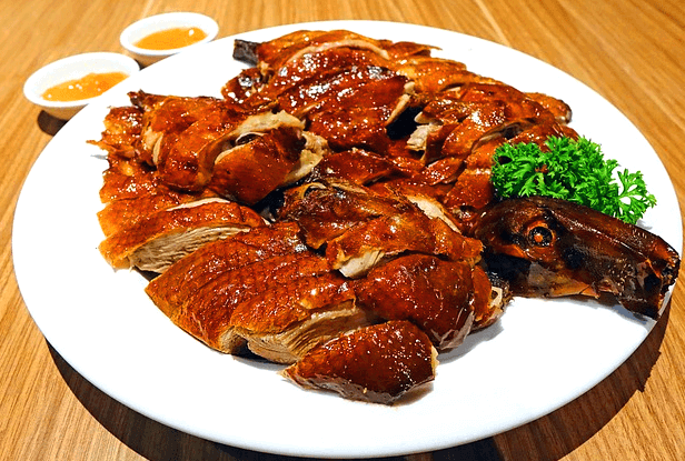 둥그런 하얀 접시에 잘 썰어진 북경 오리구이 요리가 한가득 있다. 껍질은 갈색이고 매끄럽다.