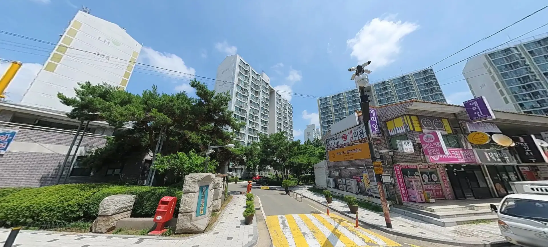 국민임대아파트 능곡샘터3단지 아파트입구의 전경이다. 상가와 아파트 현판이 보인다.