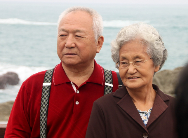 해변에서 함께 있는 노부부가 같은 방향을 바라보고 서 있는 모습