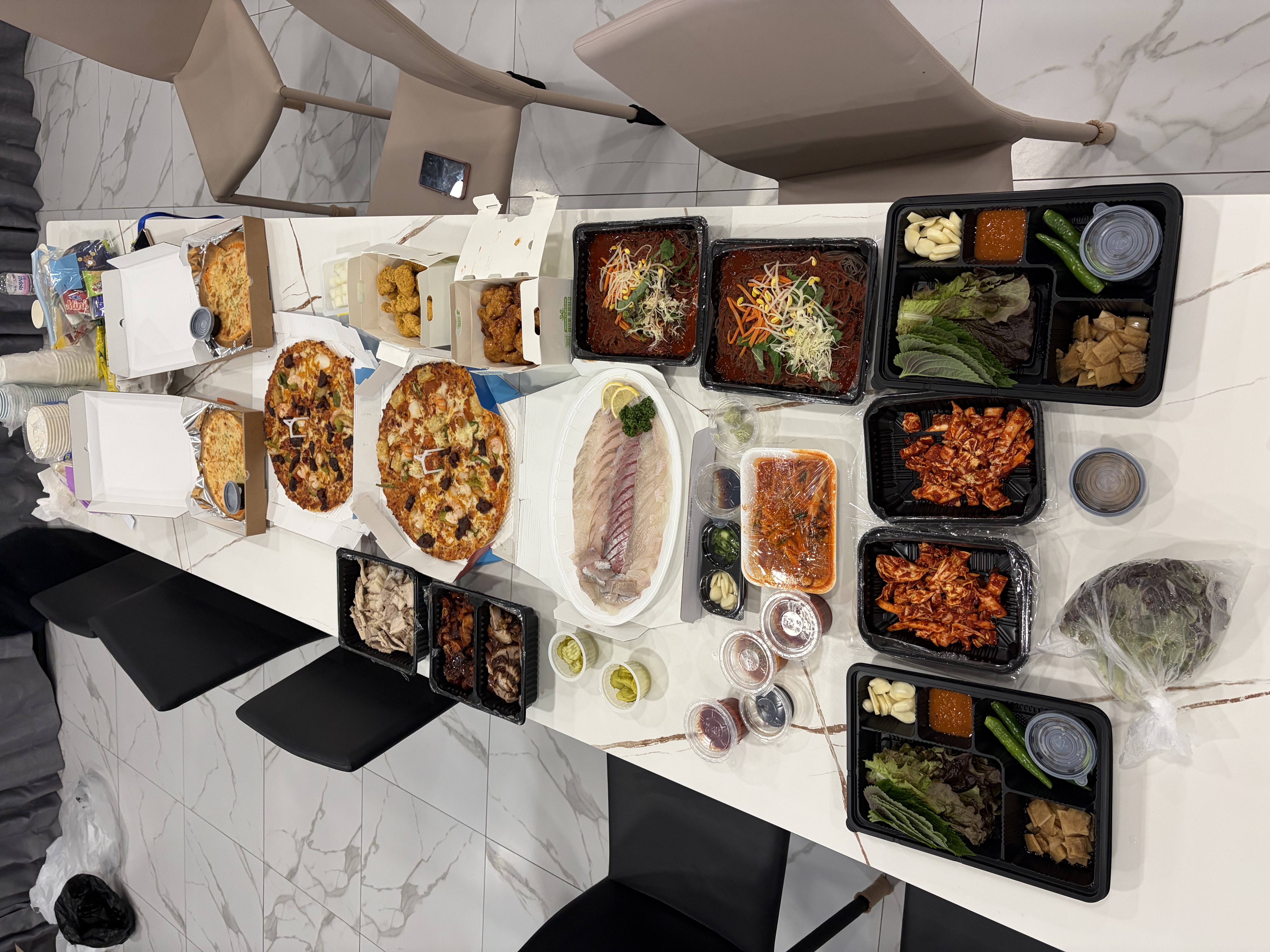 테이블 위에 가득 차려진 회, 피자, 치킨 등 다양한 야식 음식들