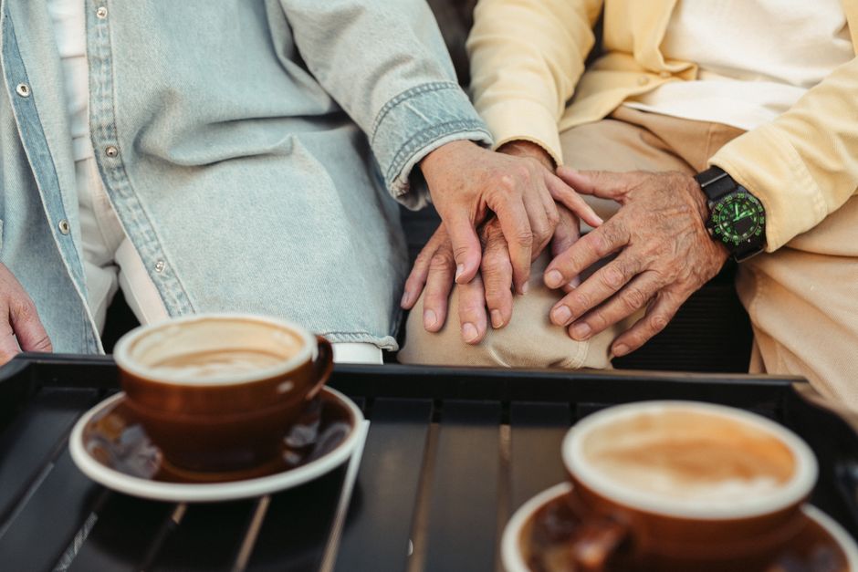 Senior couple enjoying coffee together, holding hands in a touching moment.
