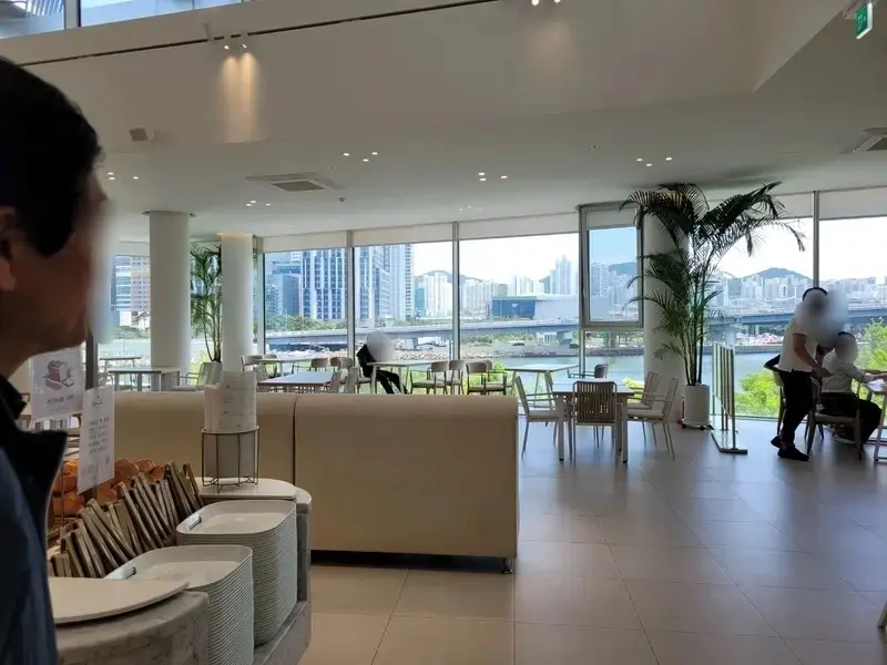 부산 해그리다카페 실내에서 보이는 넓은 창과 수영강, 마린시티 고층 빌딩이 어우러진 탁 트인 전망과 쾌적한 좌석 공간