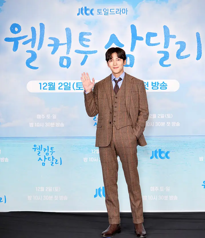 파란색 바다배경 웰컴투삼달리 글자 - 앞 지창욱이 검은 갈색 양복을 입고 포즈를 취하고 있는 모습