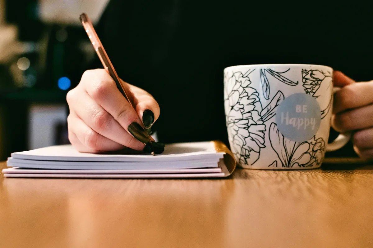 펜을-잡고있는-여자의-손과-머그컵