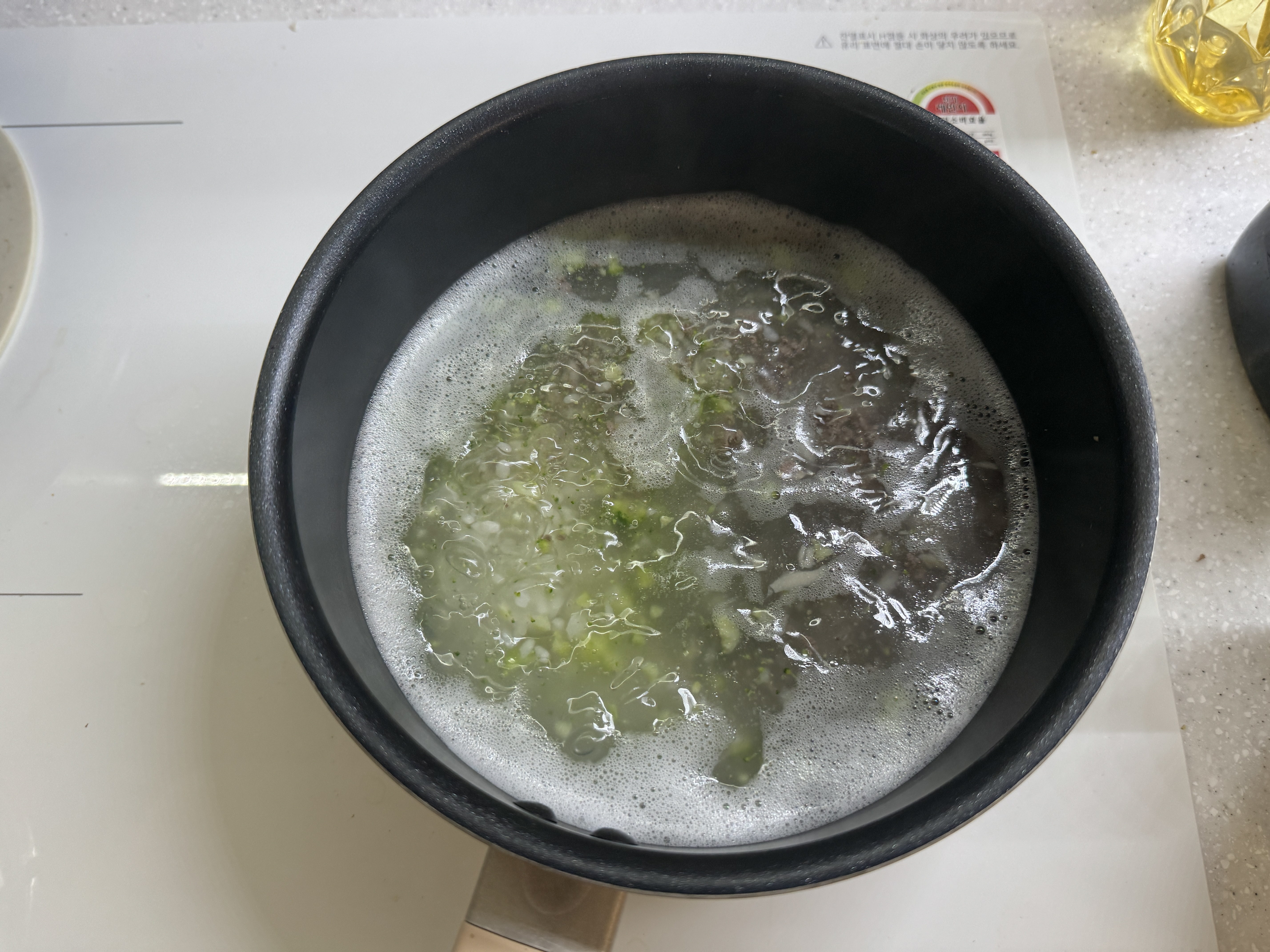 냄비에 쌀과 브로콜리, 소고기, 버섯을 넣고 끓이는 사진