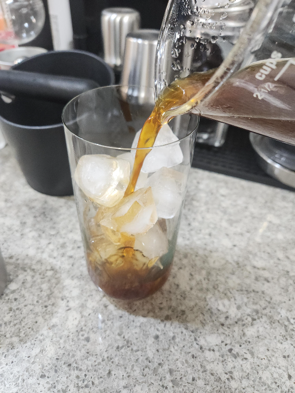 얼음컵에 추출된 커피를 붓고 있다.