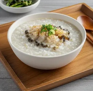 전복과 다진 파가 올려진 따뜻한 전복죽 한 그릇.