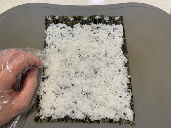 Spreading rice thinly over seaweed for Rumi Kimbap