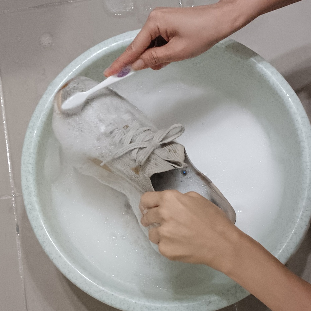 부드러운 칫솔로 흰 운동화 밑창과 틈새 오염을 닦는 과정