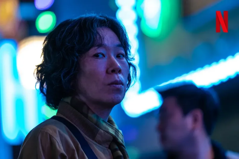 어느 네온사인이 있는 밤거리를 배경으로 허름한 복장과 용모를 하고 있는 마스크걸의 김경자