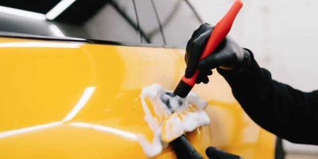 셀프 세차 방법에 대한 포스팅 썸네일로 노란 자동차의 손잡이 부분을 브러시를 사용해 디테일하게 세척하고 있는 모습