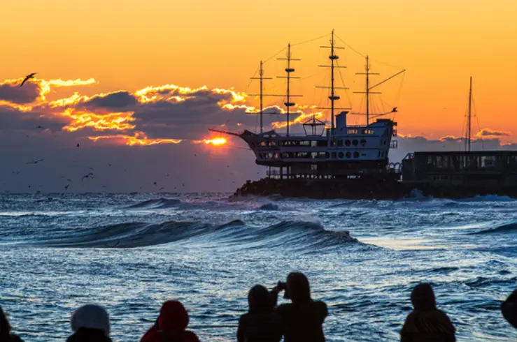 붉은 해가 솟아오를는 배경을 뒤로한 커다란 유람선