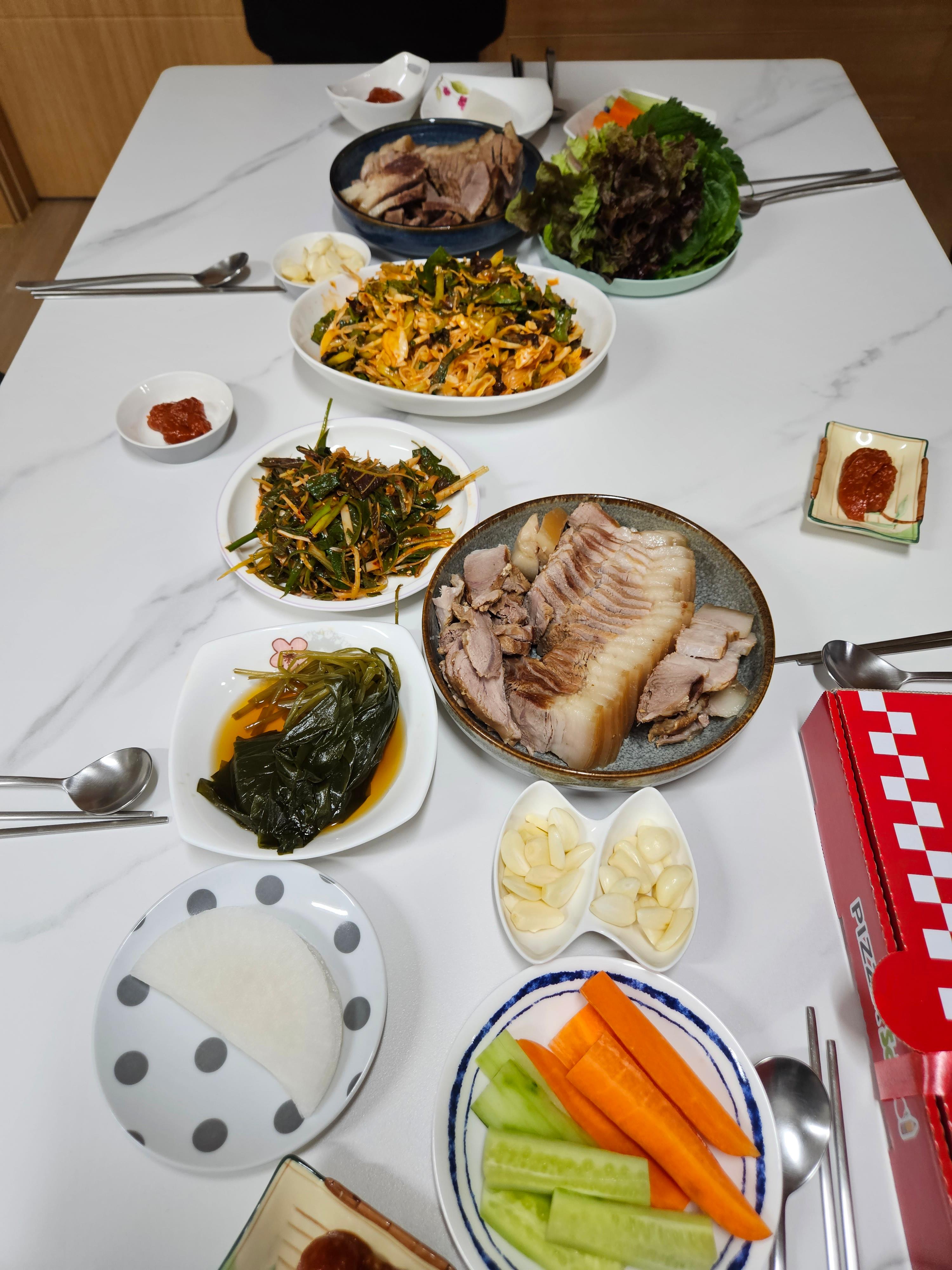 푸짐하게 차려진 돼지고기 수육과 각종 야채, 반찬이 놓인 식탁 상차림