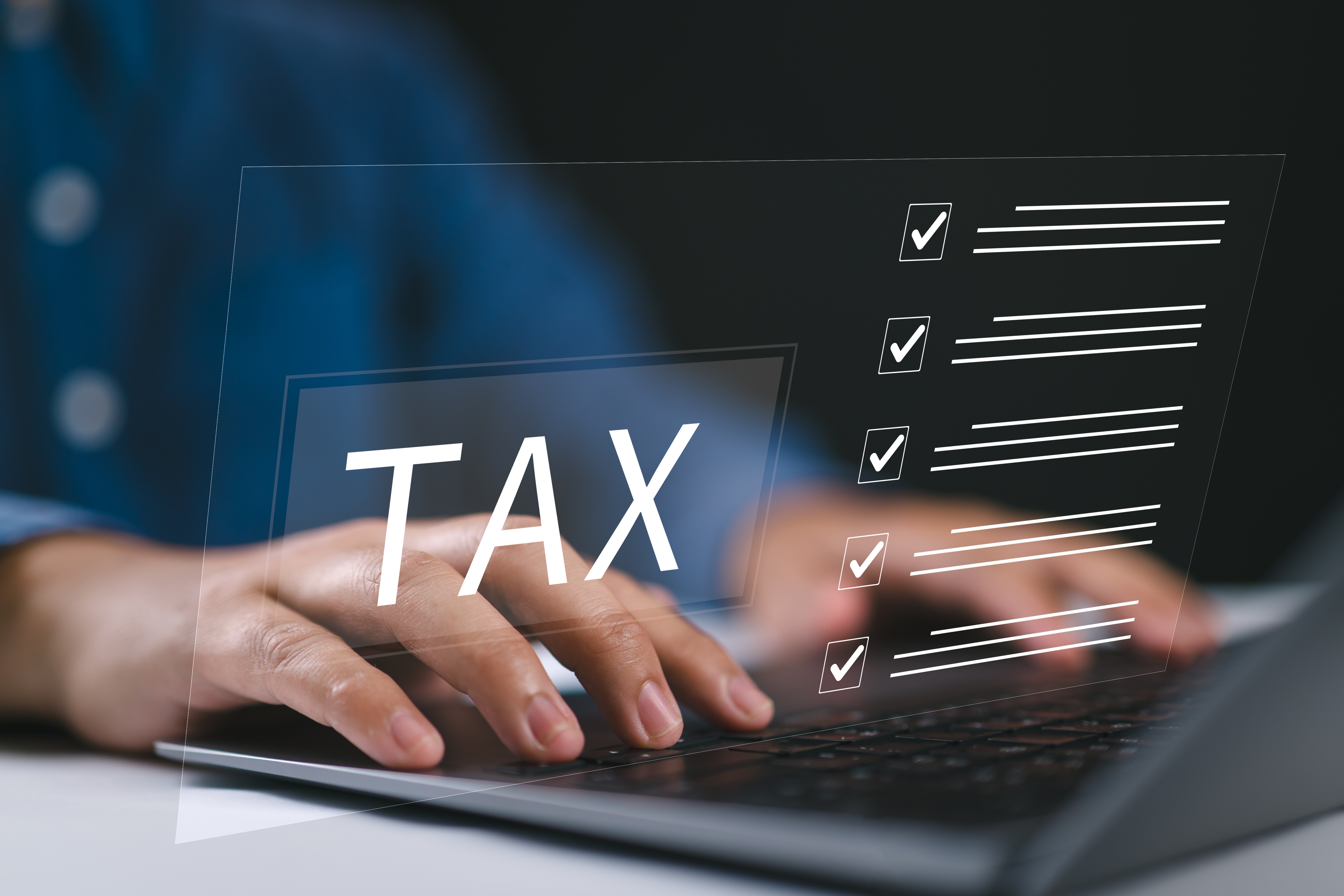 체크리스트와 TAX 문구가 표시된 화면을 보며 노트북으로 세금 공제 항목을 정리하는 손
