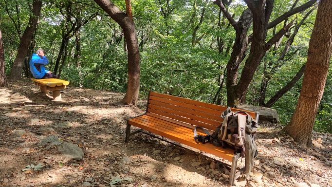 쉼터&#44; 등받이 없는 의자 1에 앉아 쉬고 있는 파란 등산복 남성 1&#44; 우측에 깨끗한 벤치 1&#44;