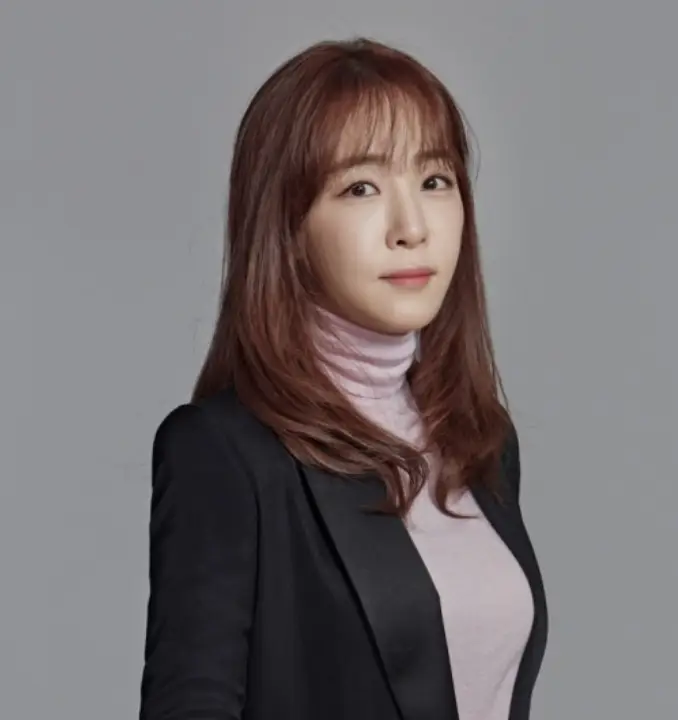 회색배경 검은색 정장을 입고 긴생머리를 늘어뜨린 김이나