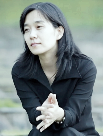 한강-작가-손을-모으고-무언가를-바라보는-표정으로-앉아-있는-모습