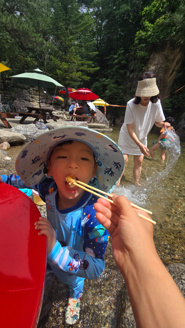 계곡에서 놀다가 아빠가 주는 감자전 을 먹는 아이 사진