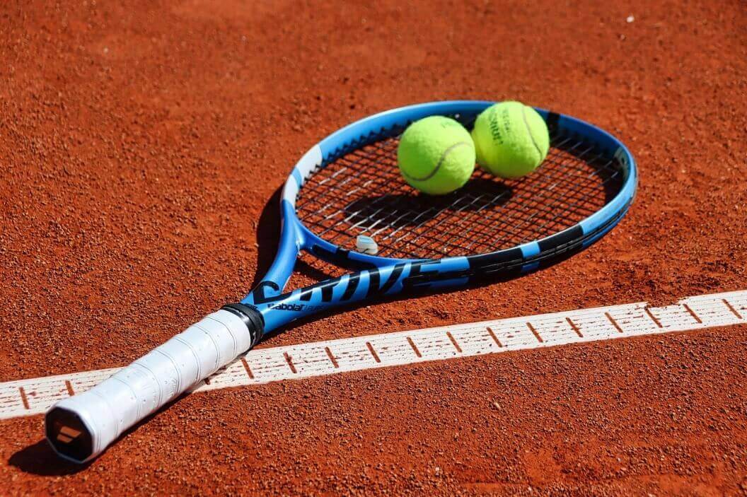 앙뚜까 코트에 바볼랏 라켓과 그 위에 노란 테니스공 2개가 있는 사진