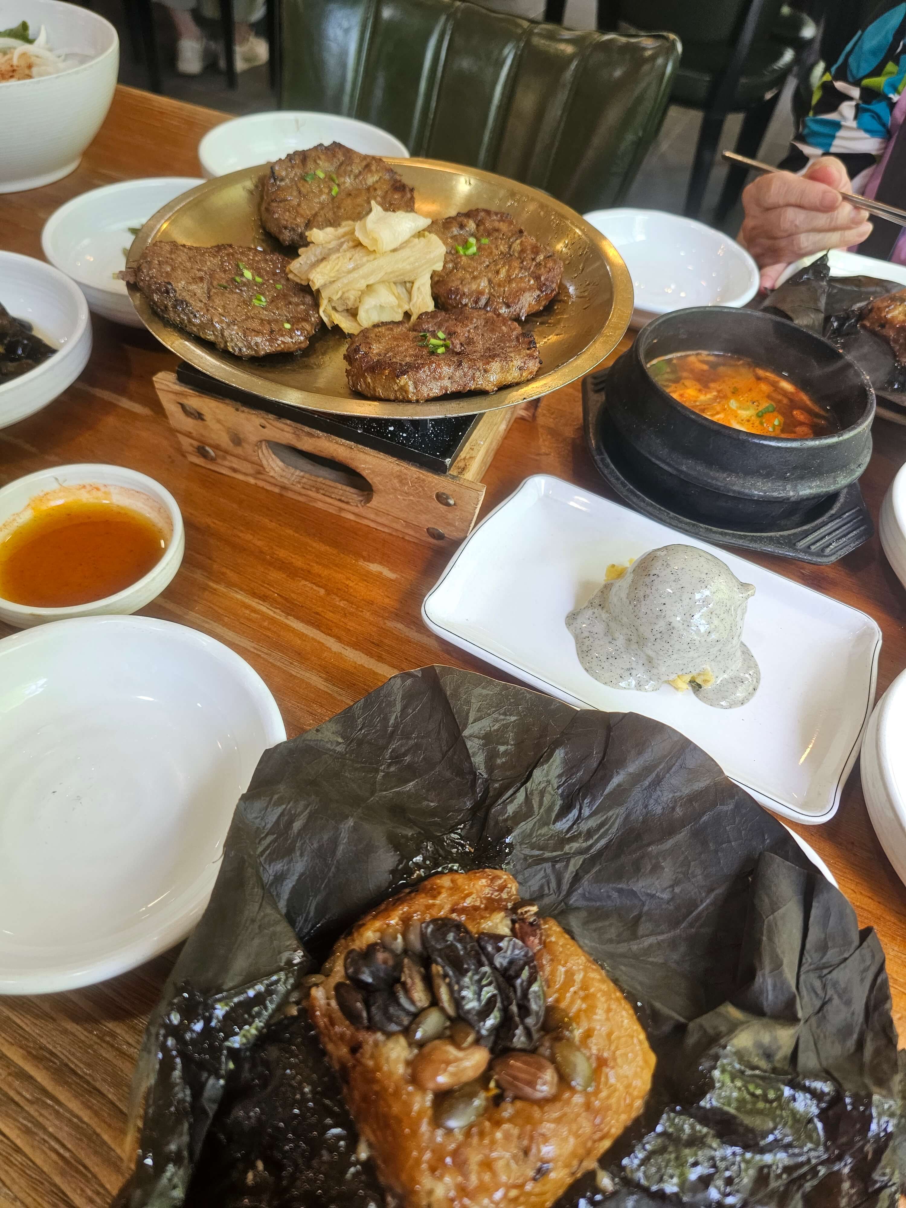 테이블위에 연잎밥과 한우떡갈비 와 된장찌게 그리고 밑반찬