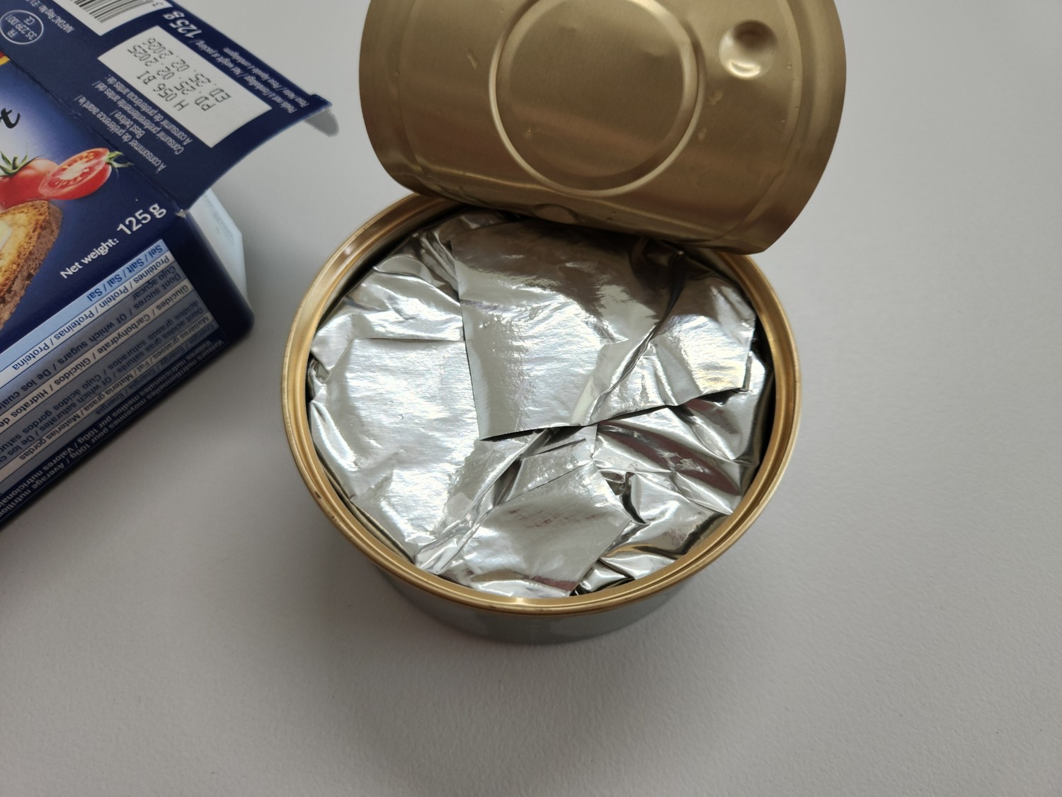 캔이 열려 있고 캔 안에 은색 종이가 보인다