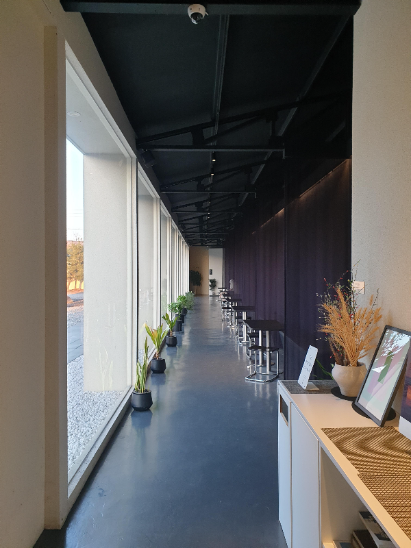 복도를 따라 일직선으로 놓여있는 테이블과 의자들. 창 밖으로 외부가 보인다.