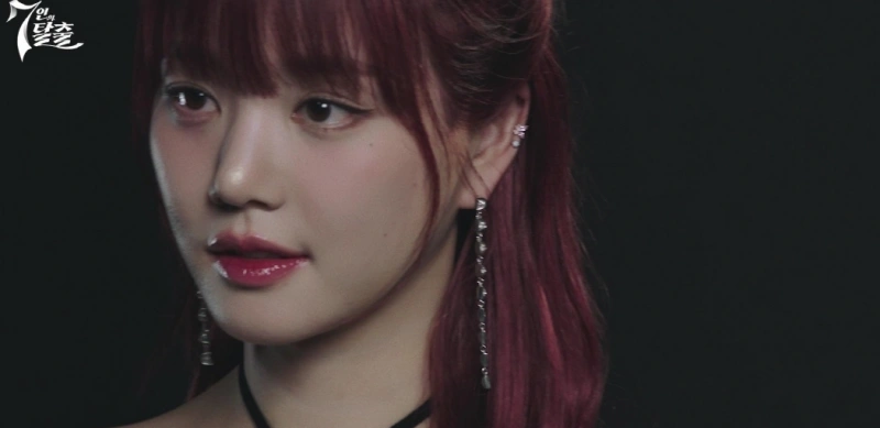검은 배경에 화려한 화장과 핑크색 헤어 스타일을 하고 있는 드라마 7인의 탈출에서 한모네 역을 연기하는 배우 이유비