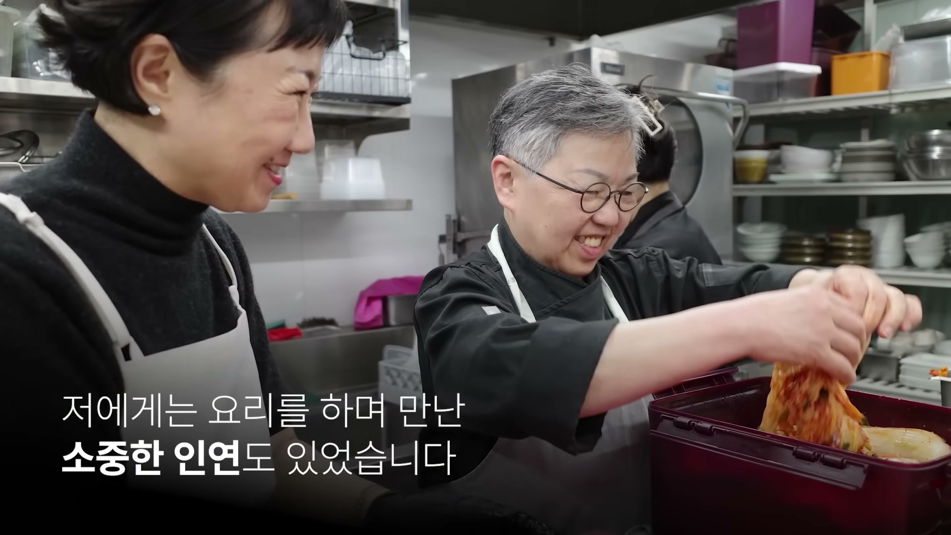 우정욱 셰프가 다른 셰프와 함께 김치를 만들며 환하게 웃는 장면.