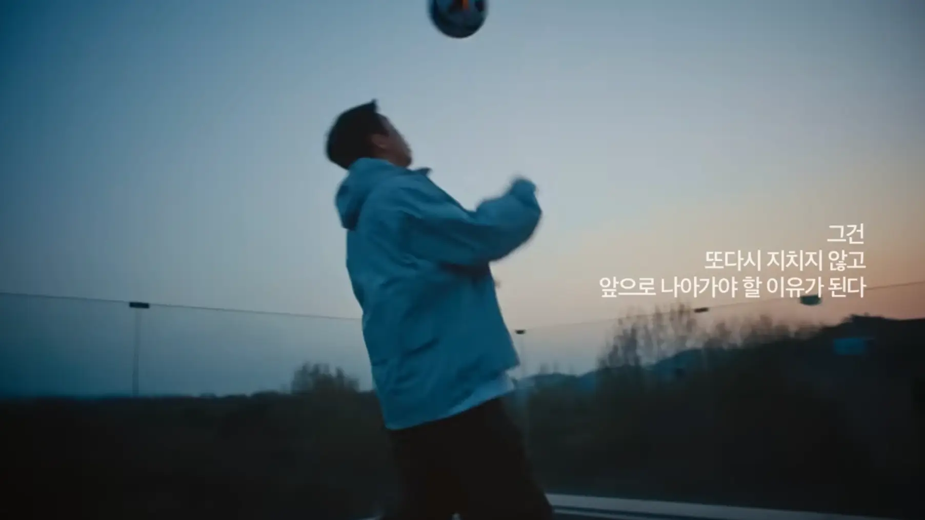 새벽녁 흰 점퍼를 입고 야외에서 공을 차고 있는 임영웅