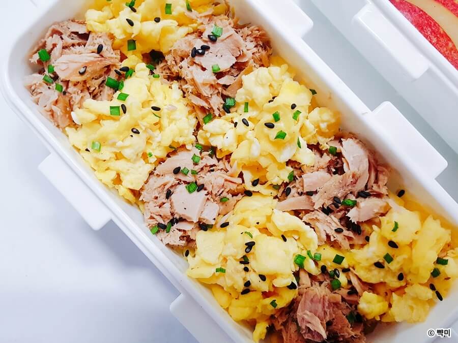 도시락통에 밥을 담고 참치와 스크램블에그를 격자무늬로 올린 클로즈업 장면