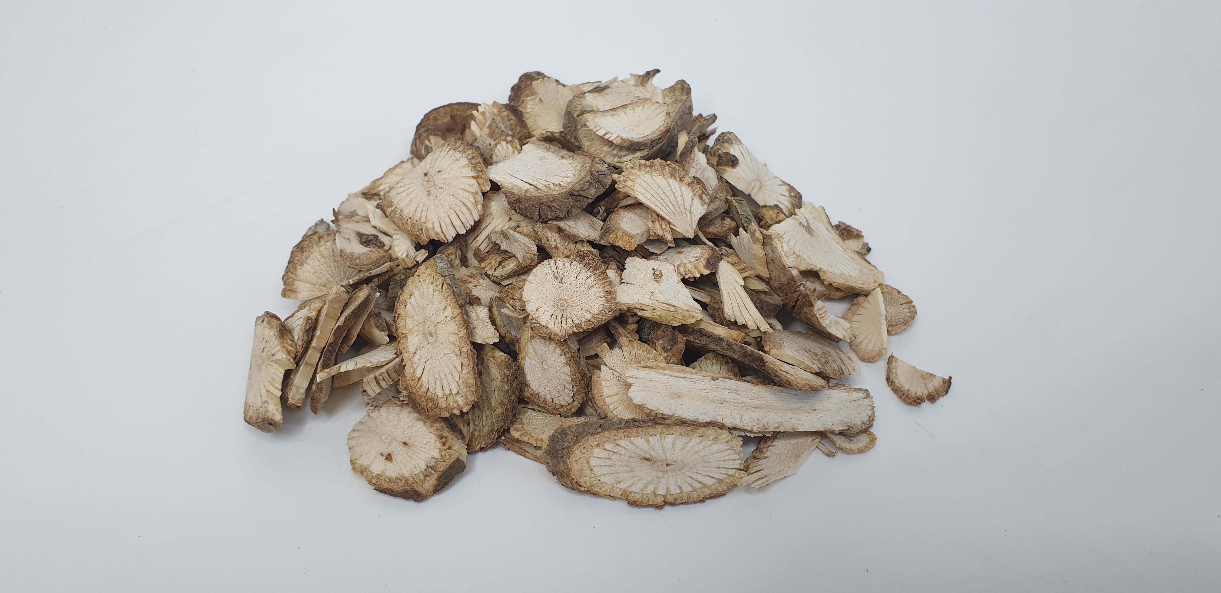 야생에서 채취를 한 목통나무의 뿌리인 목통을 잘 세척한후에 건조한 것을 편으로 썰어서 하얀 바닥 위에 수북하게 쌓아두고 찍은 사진