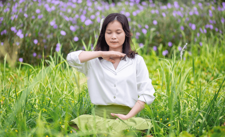 여성이 풀밭에 앉아 명상하는 모습