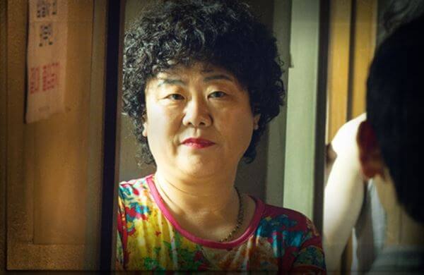 이정은 배우가 의문스러운 미소를 지으며 주인공을 쳐다보는 장면