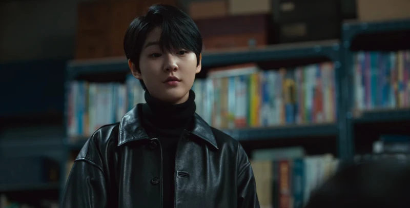 책장을 배경으로 검은 가죽자켓을 입고 짧은 헤어로 상대를 내려보는 차현주를 연기하는 김새론