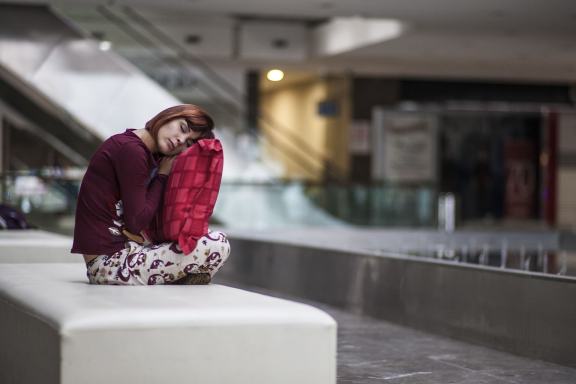 길거리 의자에 앉아서 쿠션에 기대어 자는 여자